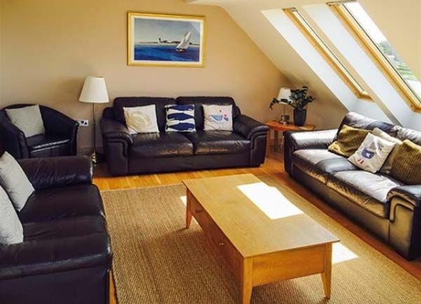 1st floor lounge with long velux windows down to floor level, 3, 3-seater sofas armchair and doffee table.