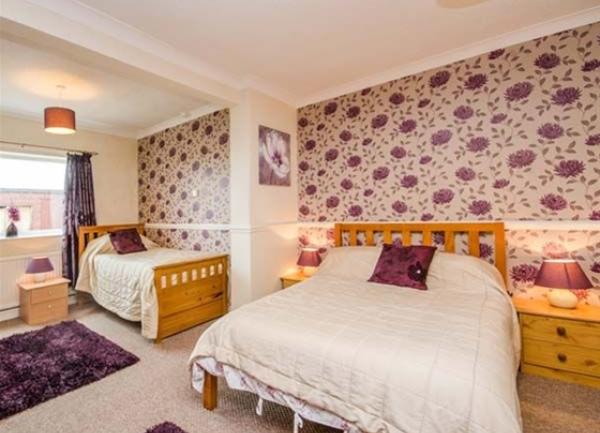 Family bedroom with double and single beds and bedside tables with lamps.