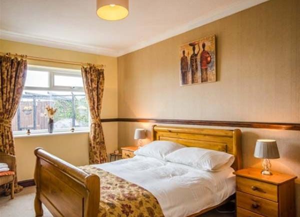 Double-bedroom with wooden bed, twin bedside cabinets and table lights.