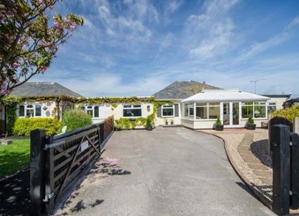 Gated driveway to a long, single torey modern house.