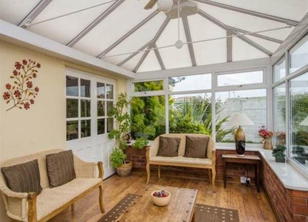Glass-roofed conservatory with sofas and coffee table.