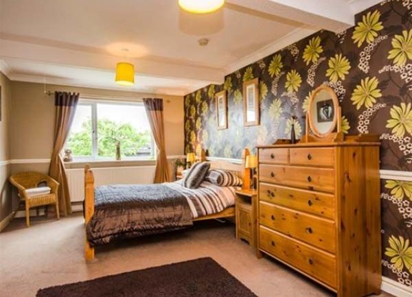 Double bedroom with bed, chest-of-drawers, bedside cabinets and armchair.