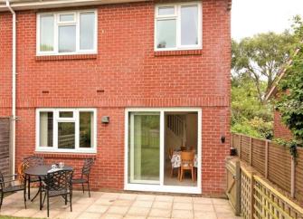 Exterior of a modern holiday home with French Windows overlooking a paved courtyard garden.