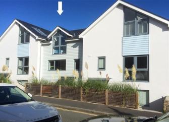 Exterior of a contemporary terraced seaside holiday cottage with floor-to-ceiling bedroom window.