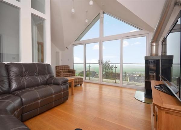 Lounge with wrap-around sofa, widescreen TV and bi-fold windows to a balcony.