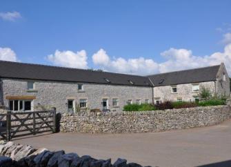 Converted barns overlook a courtyard garden bordered by a low stone wall.