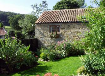 North Yorkshire barn conversion surrounded by a lawn, trees and mature shrubs