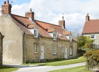 the exterior of a stone built holiday cottage in North Yorkshire with terracotta roof and grassy lawns.