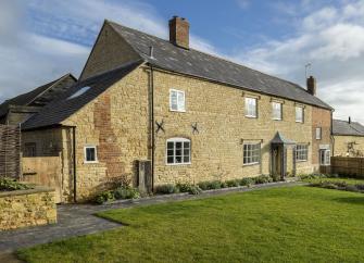 Large, stone-built farmhouse with a spacious lawn.