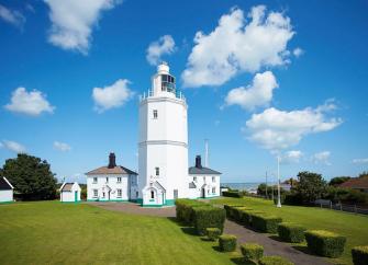 A lighthouse and buildings now converted to holiday cottages gleams in the summer sun in Broadstairs.