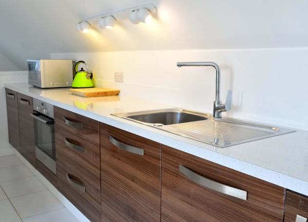 A row of fitted kitchen units with an oven, microwave and kettle.