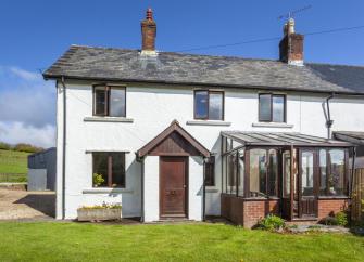Semi detached cottage with conservatory and lawned garden.