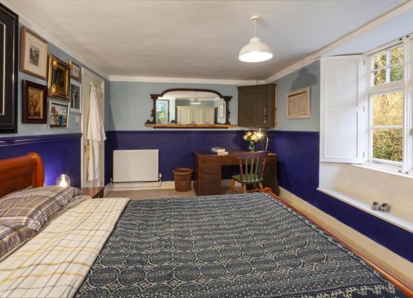 Double bedrooms with a bed facing a large window to a garden. A desk and a mirror are at one end.