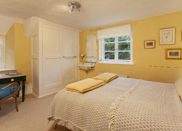 A double bedroom with a bed, easy chair and a washbasin.
