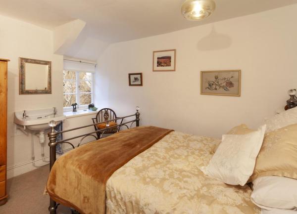 A double bedroom with a bed, wardrobe, bedside chair and washbasin.