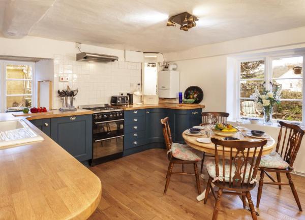 A dual aspect kitchen-diner with fitted cupboards and a dinner table laid for breakfast.