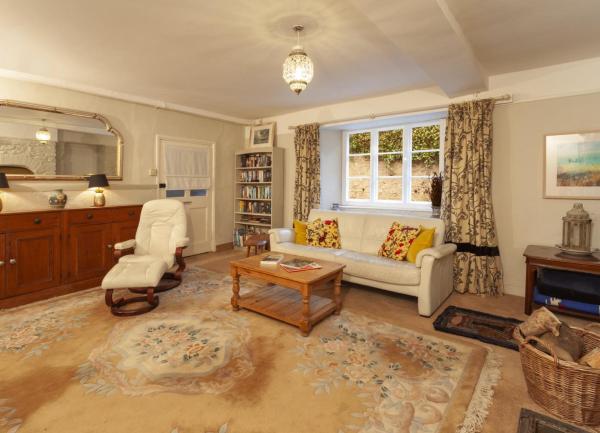 A carpeted lounge with a sofa, armchair and fitted cupboards.