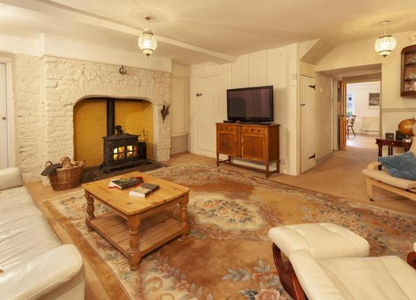 A lounge with an inglenook fireplace housing a wood burner, a TV, sofa and recliner chairs.