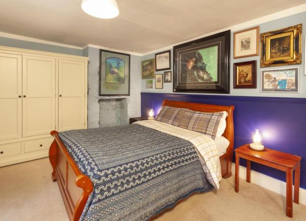A double bedroom with a bed, bedside tables, fitted wardrobe and a wall covered with framed paintings.