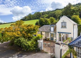 A 2-storey house with a ground-floor extension overlooks a courtyard and mature garden.