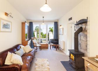 A Exmoor coastal cottage lounge with leather sofas, French windows to a garden.
