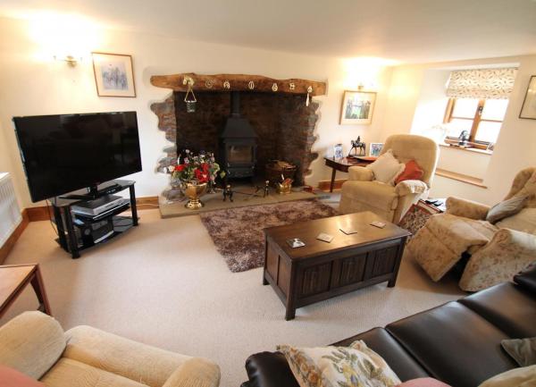 A spacious lounge with an inglenook fireplace and widescreen TV