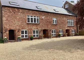 A long, stone-built barn conversion to form a Quantock Hills holiday cottage overlooks a courtyard.