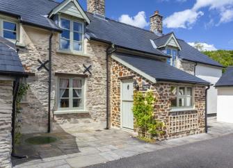 Exterior of a traditional stone-built Exmoor cottage overlooking a quiet village lane.