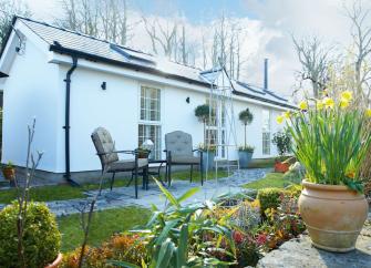 Single storey holiday cottage in Glamorgan with a terrace bordered by a low stone wall.
