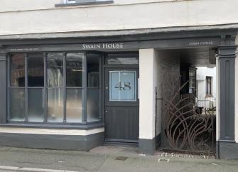 Entrance and front windows of seaside shop converted to a holiday cottage.