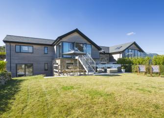 Exterior of a large and luxurious holiday home in St. Ives overlooking a wide lawn.