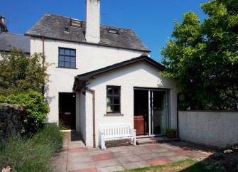 Exterior of a holiday cottage in Cark-in-Cartmell overlooking a small patio and lawn.