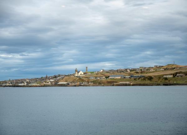 A spit of land with houses huts into the sea.