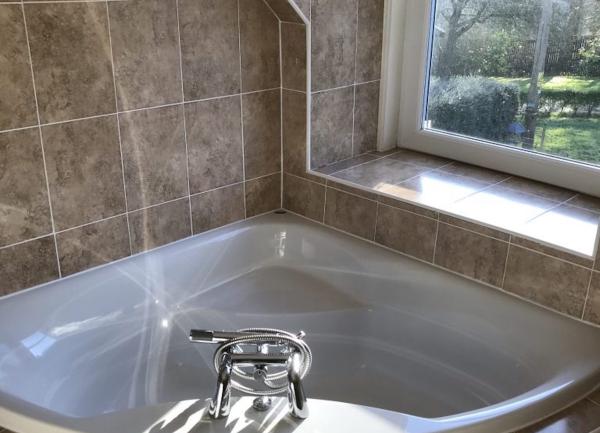 Corner bath in tiled bathroom.