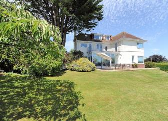 exterior of a large holiday home overlooking an extensive garden with a large lawn.