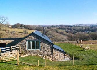Exterior of a stone-built Dartmoor holiday cottage tucked into a fold in the surrounding Devon countryside