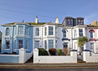 Exterior of a two-storey period house with large bay windows on both floors overlooking a small front garden.