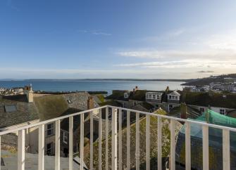 A view across roof tops to the harbour wall and ocean from the deck of a St Ivedsholiday apartment.