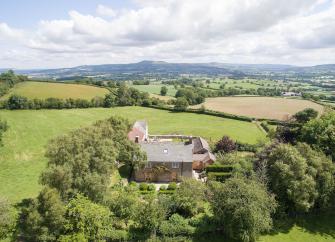 Aerial view of a small country house surrounded by trees and fields in a remote rural location near Montgomery.