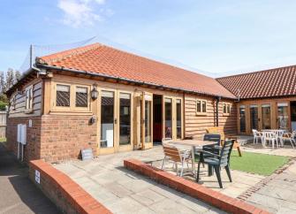 Exterior of an L-shaped holiday bungalow in Hunstanton overlooking a paved courtyard giving level access to the house