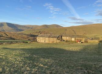 A stone-built Cumbrian farmhouse and attached barns in a remote moorland location