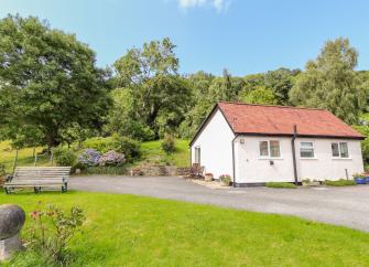 Exterior of a terracotta-roofed holiday bungalow near colwyn bay overlooking a large lawn in a rural location.