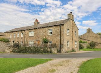 A row of three stone-built cottages with walled gardens.