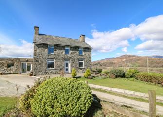 A detached, doubled-froted stone-built house with a slate roof with a slate roof, large lawned garden and views of Snowdonia/