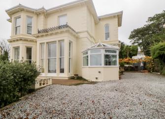 An exterior of s Victorian holiday villa in Torquay with ample car parking space in front.