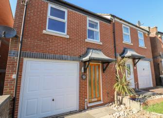 Exterior of a contemporary house with  a built-iin garage, smal front garden and a palm treein Weymouth