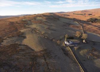 Aerial view of a country house surrounded by wild Scottish moorland.