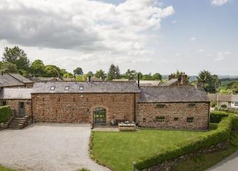 Exteriorof a large stone-built hall in Cumbria with a large lawn and parking spaces.