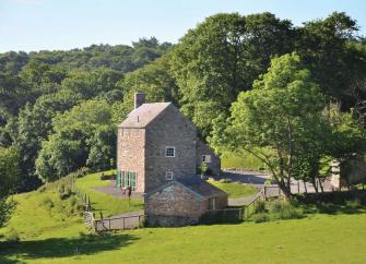 A 3-storey, brick-built Welsh holiday cottage surrounded by lawns, fields and woodland