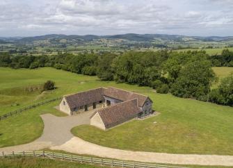 Aerial image of a Shropshire holiday barn surrounded by open fields and woods.